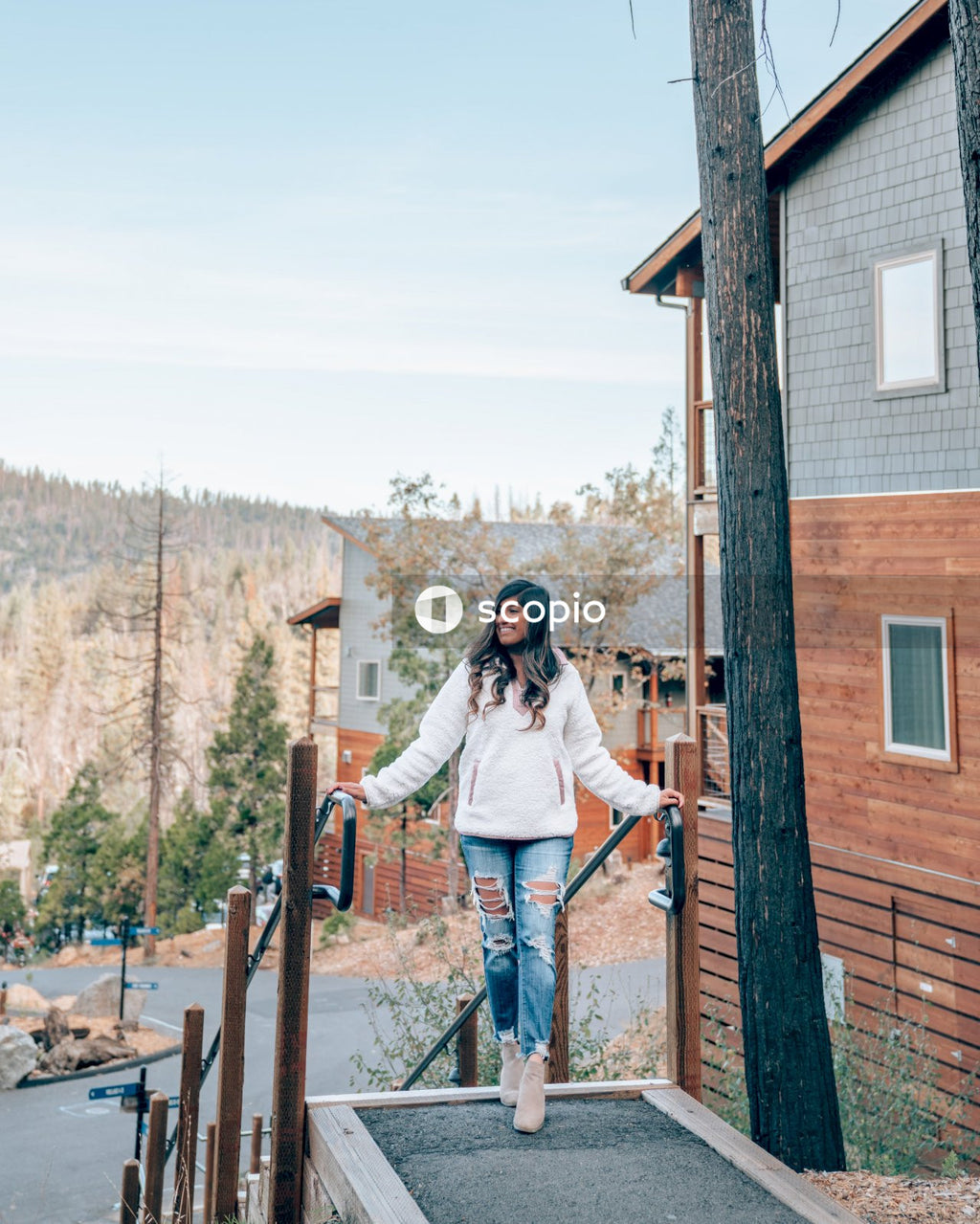 Woman in white jacket and blue denim jeans standing on brown wooden ladder