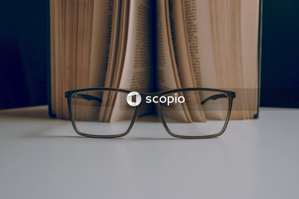 Eyeglasses before half opened  book on white table