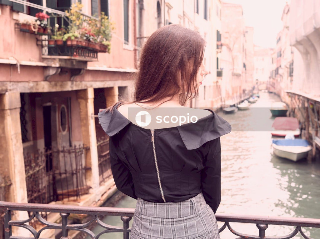 Woman in black and white striped skirt standing near body of water
