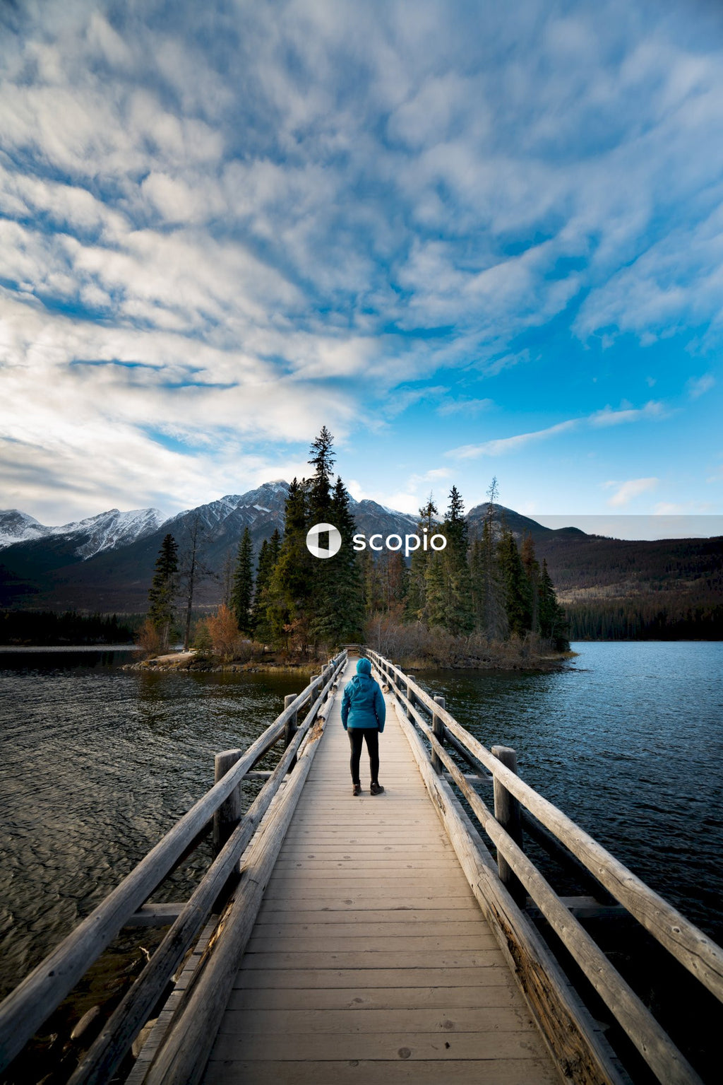 Person walking on wooden bridge over lake