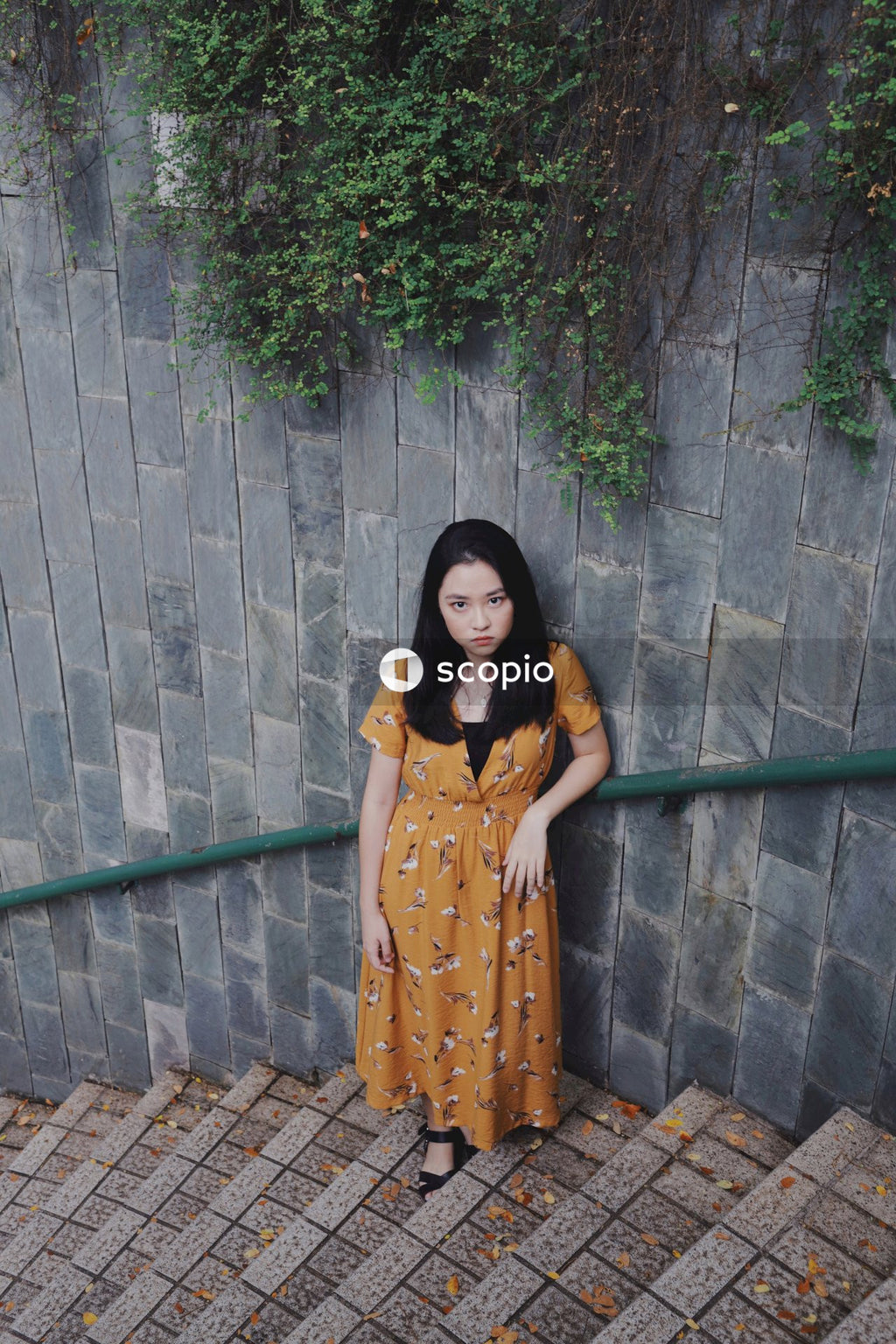 Asian woman in orange dress standing on stairs