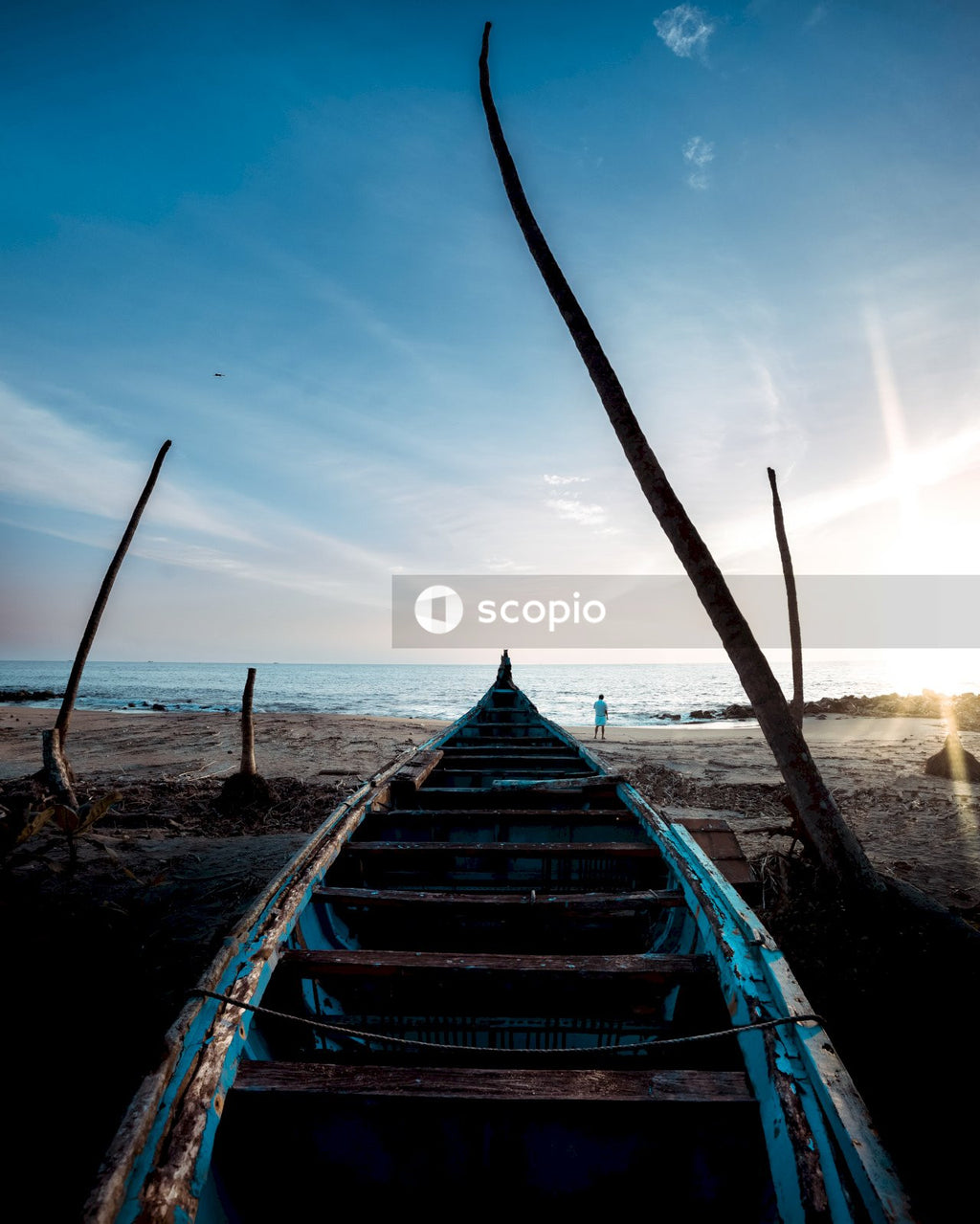 Blue and white boat on beach during sunset