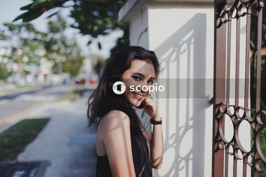 Woman in black tank top leaning on white wall