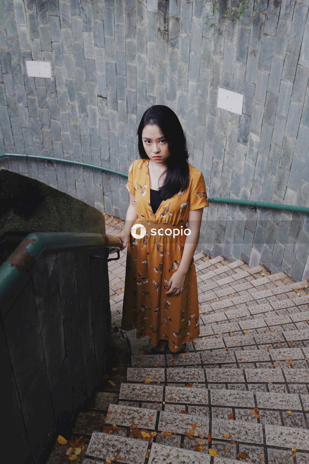 Asian woman in orange dress standing on stairs