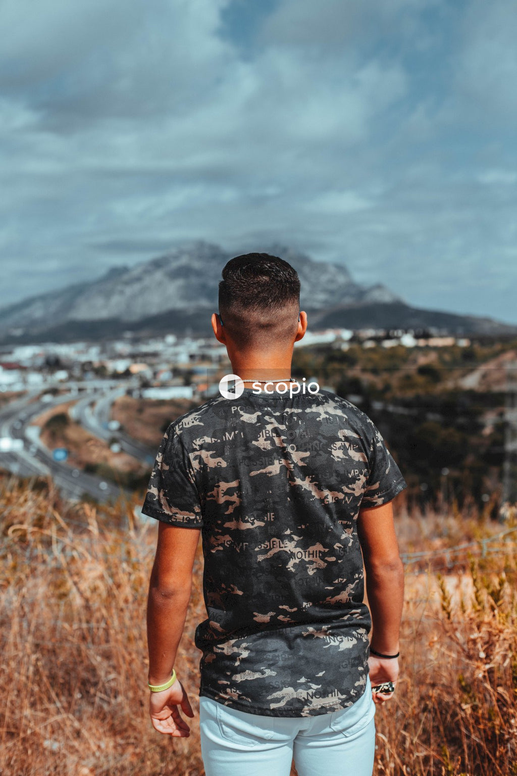 Man in black and gray camouflage crew neck t-shirt standing on brown grass field