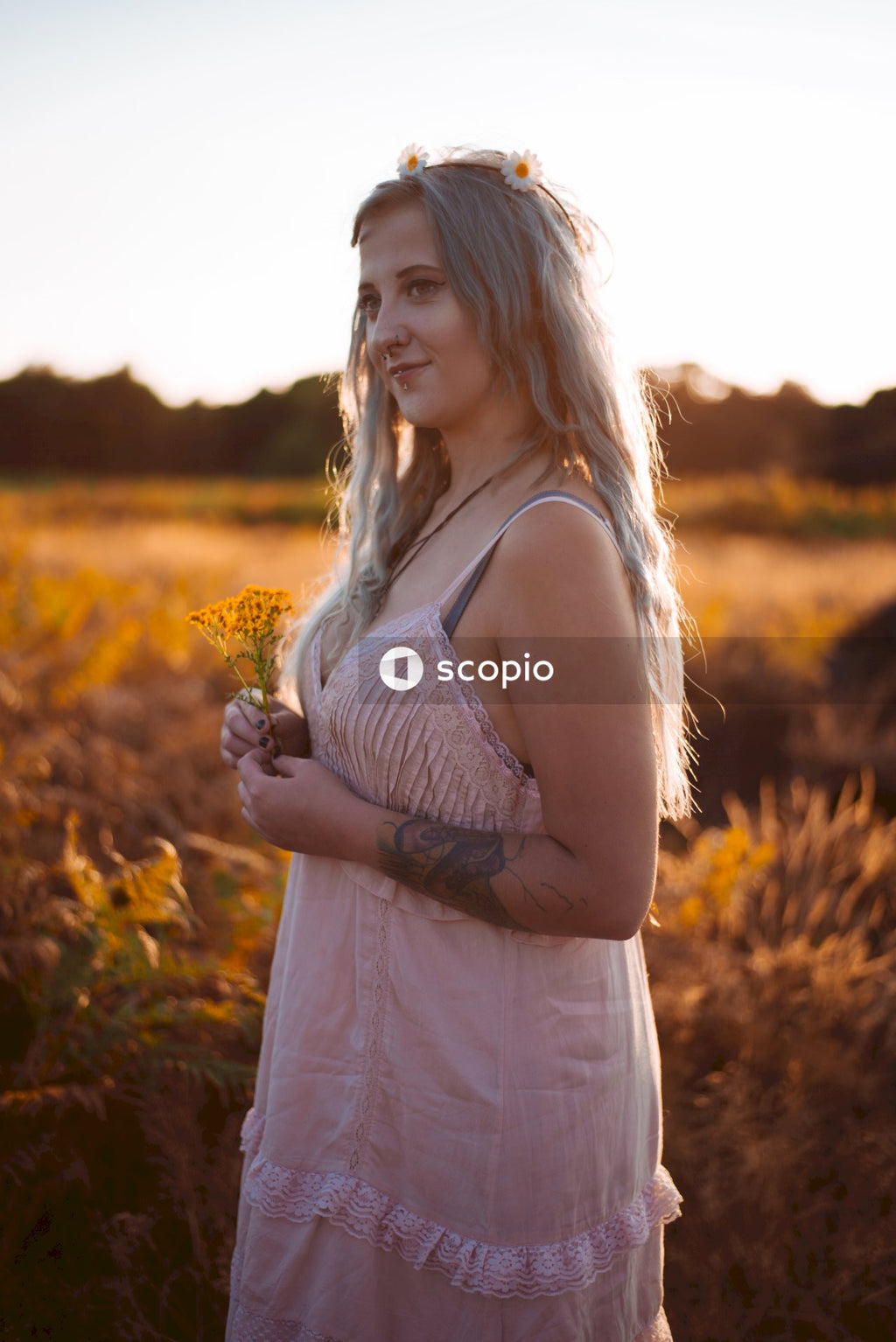 Woman in white spaghetti strap dress standing on brown grass field