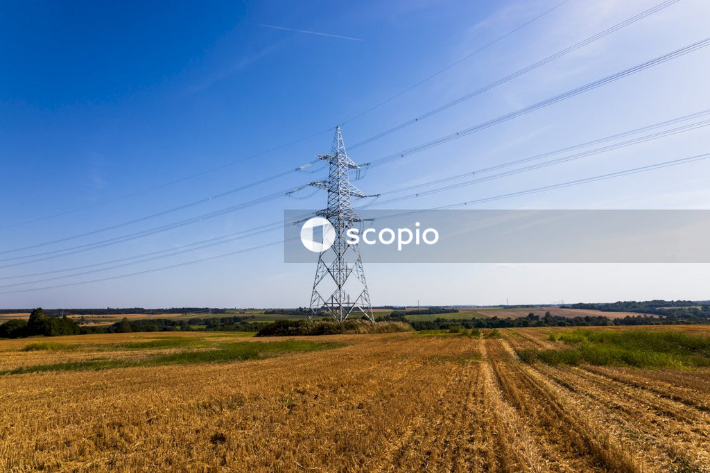 Electric tower on brown field under blue sky
