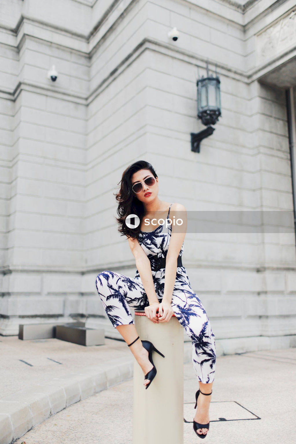 Woman in light and dark jumpsuit posing in front of building