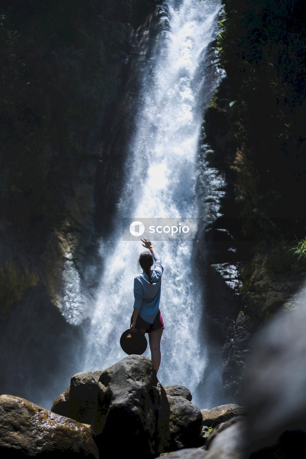 Woman standing on rocks near waterfall