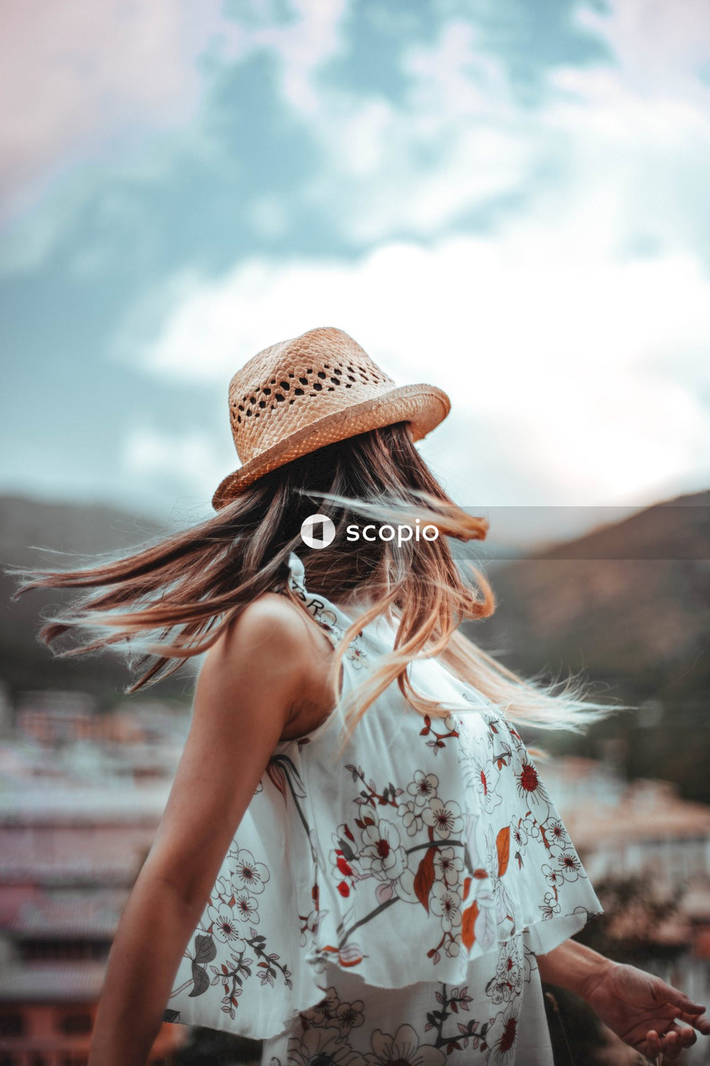 Woman in white floral dress wearing brown hat
