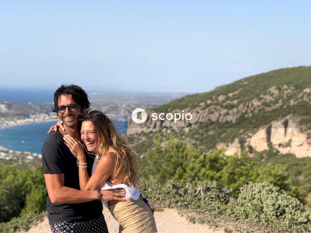 Man in black t-shirt hugging woman in white tank top on hill