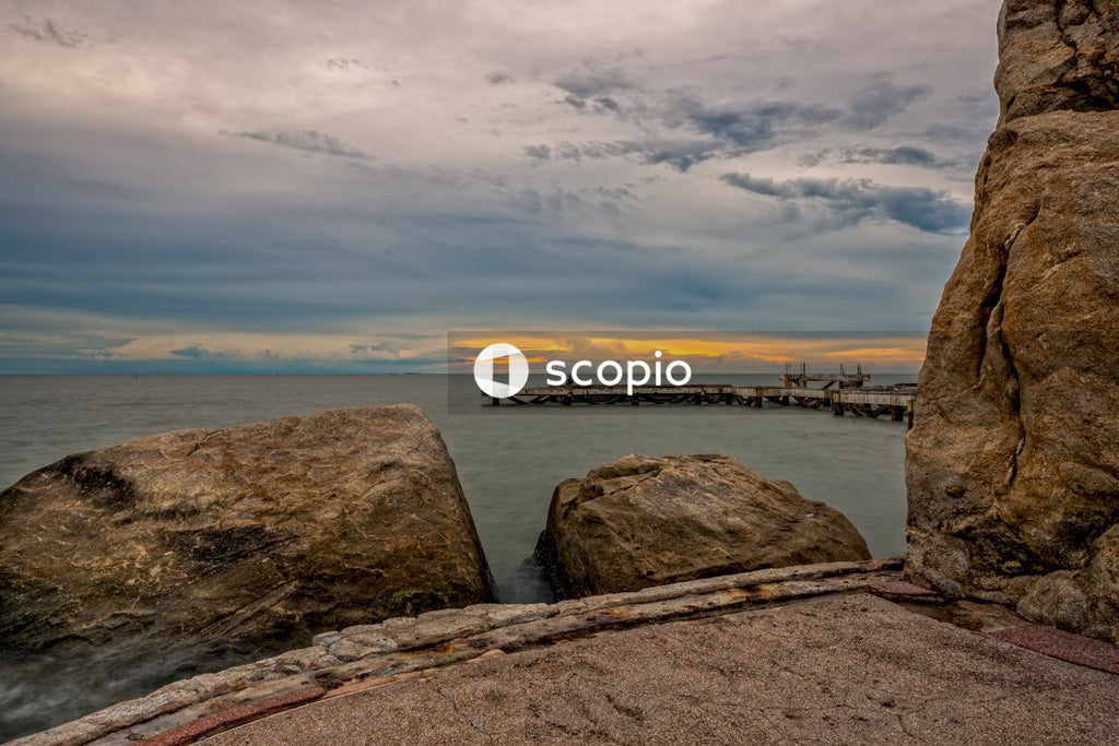 Brown rock formation on sea shore during sunset
