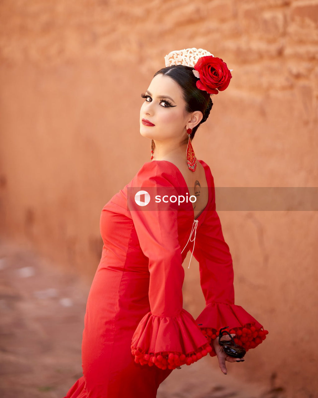 Side view of woman in Gitana dress standing against yellow rock formation