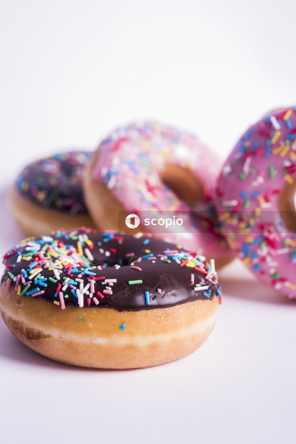 Brown doughnut with sprinkles on white surface