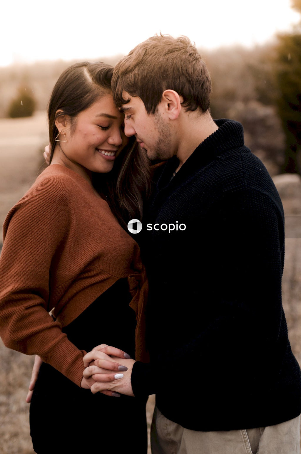 Man in black long sleeve shirt hugging woman in brown sweater