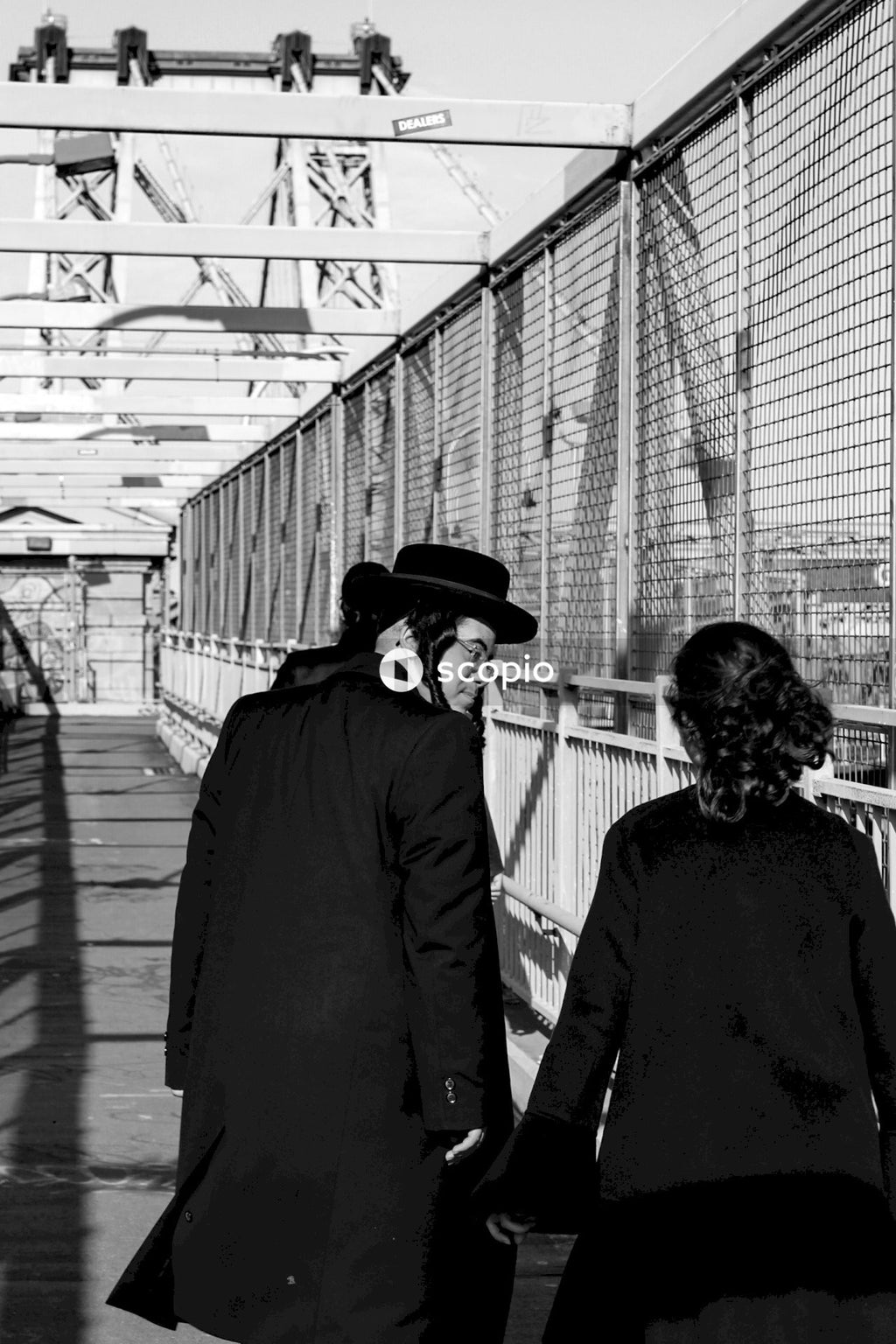 Grayscale photo of man and woman walking on bridge