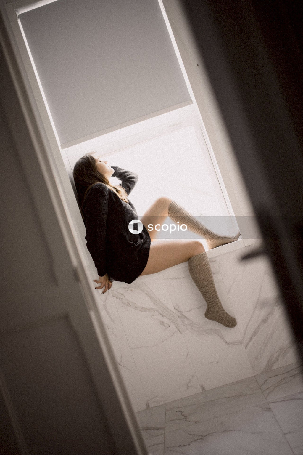 Woman in black long sleeve dress sitting on white wooden door