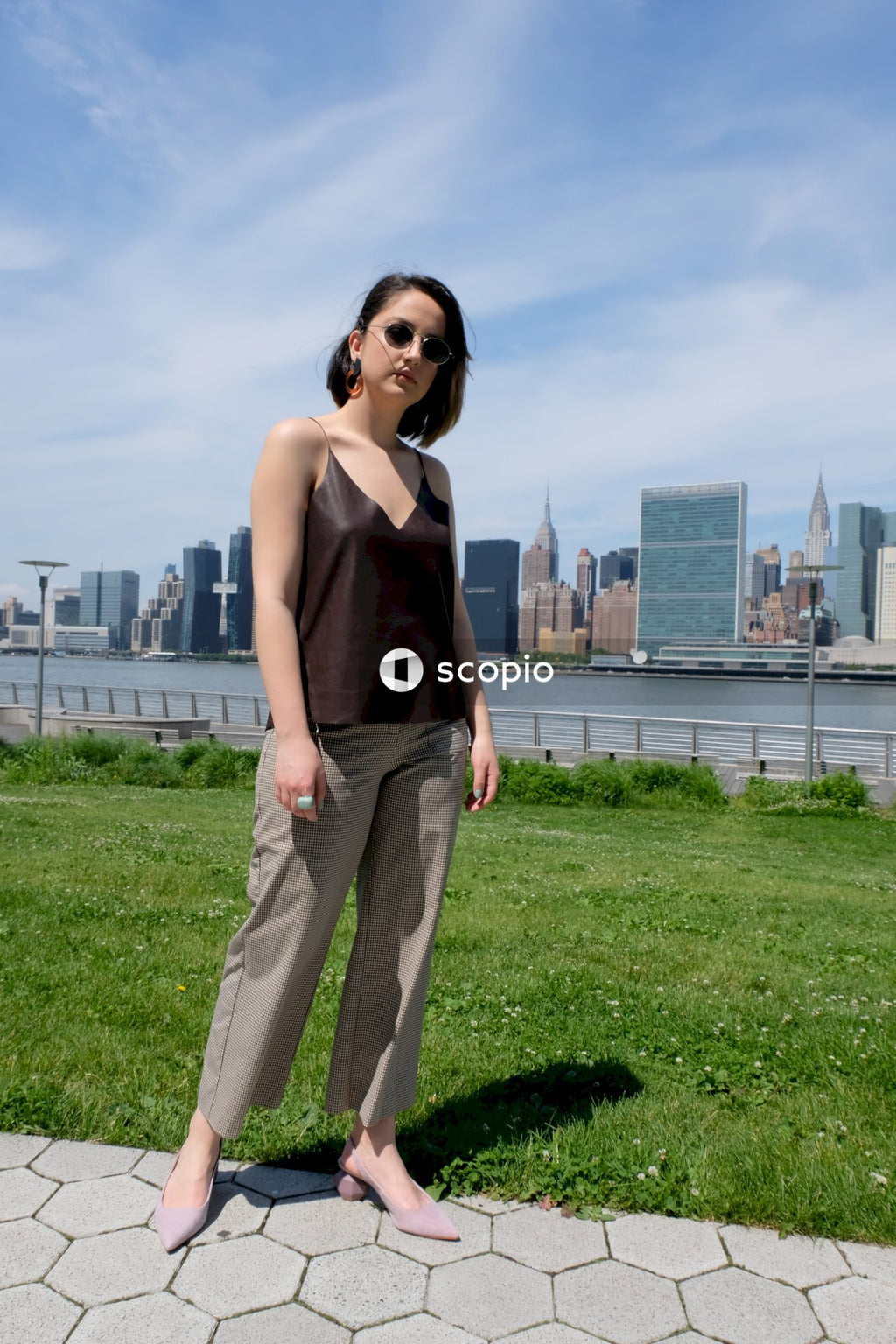 Woman in black tank top and gray pants standing on green grass field