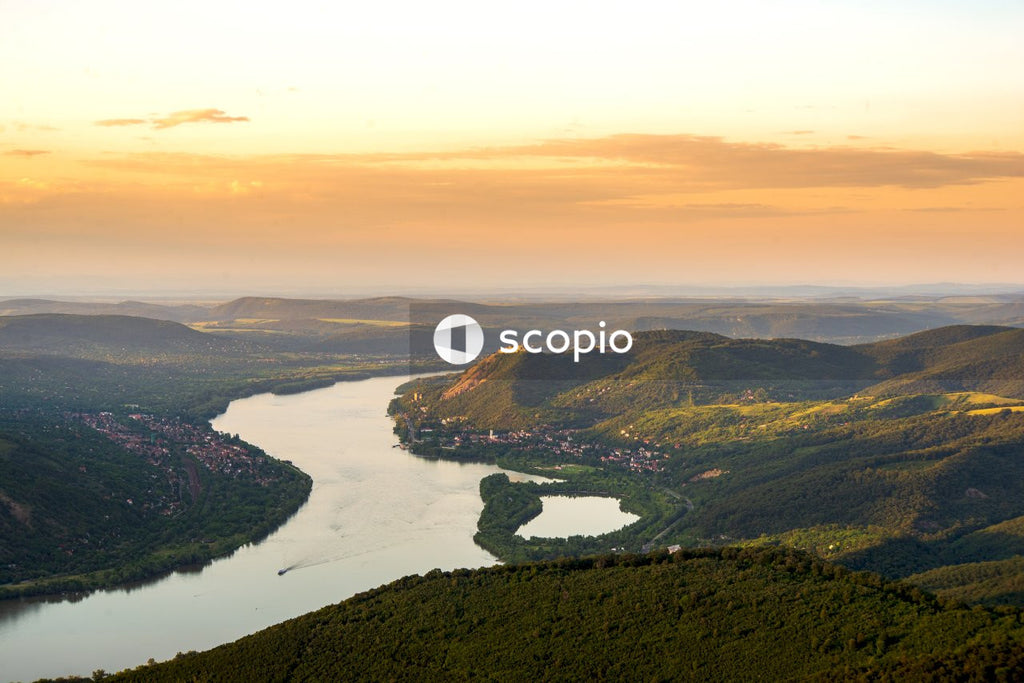 Aerial view of green mountains and river during sunset