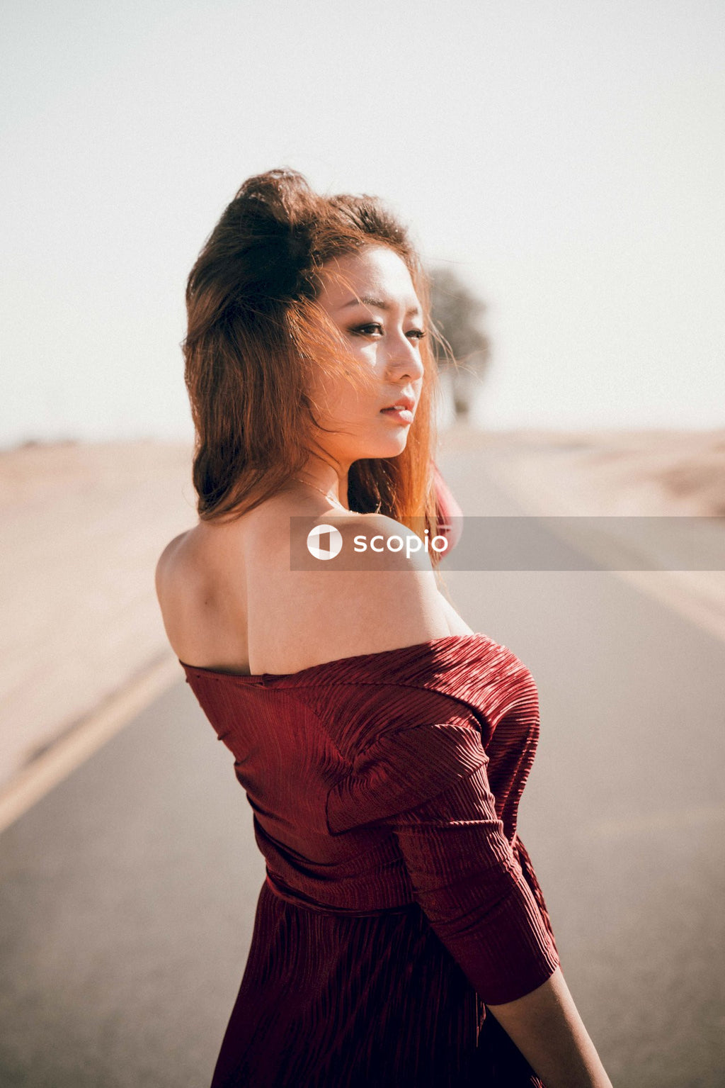 Back view of woman wearing red dress standing on road