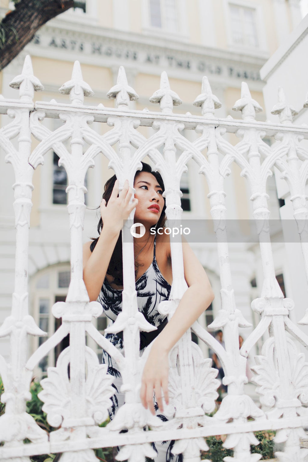 Woman in light and dark jumpsuit behind light building fence