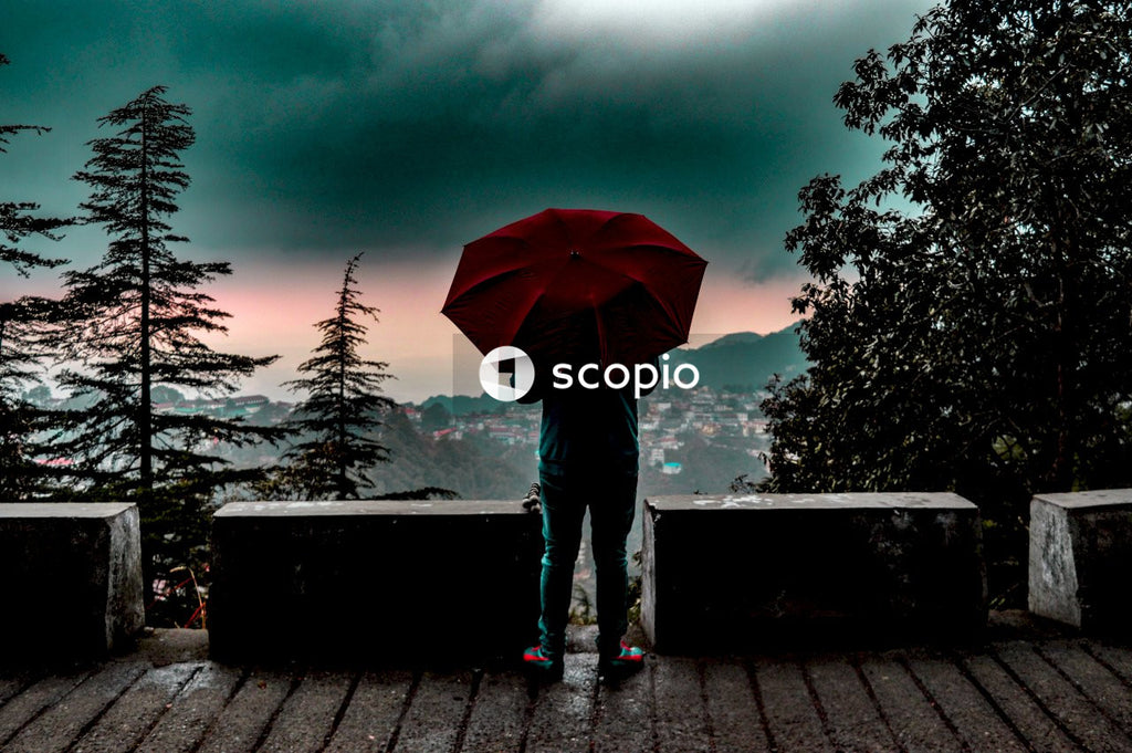 Person in blue denim jeans holding red umbrella