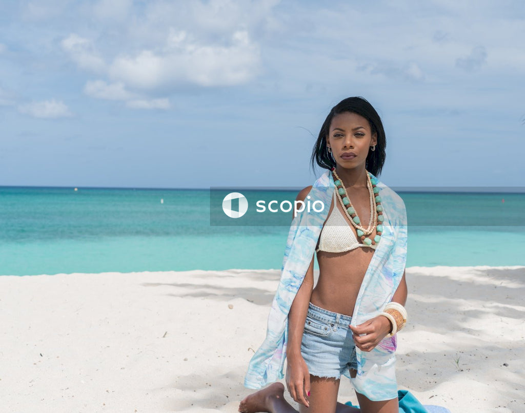Woman in white bra and blue denim shorts standing on beach