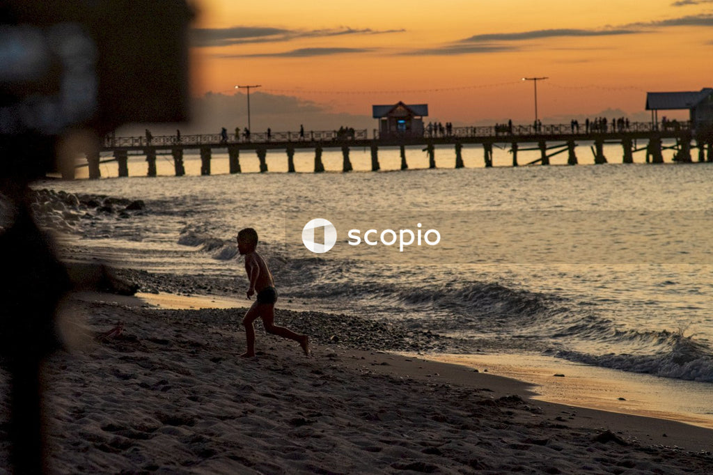 Girl in black swimsuit walking on beach during sunset