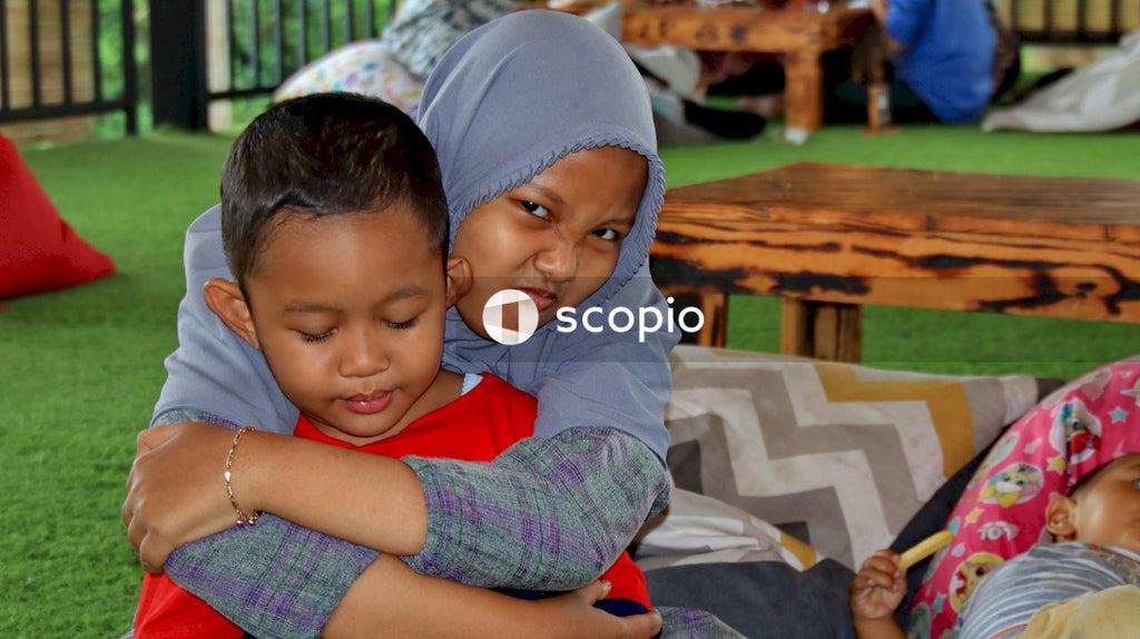 Girl in blue hijab hugging boy in gray hoodie