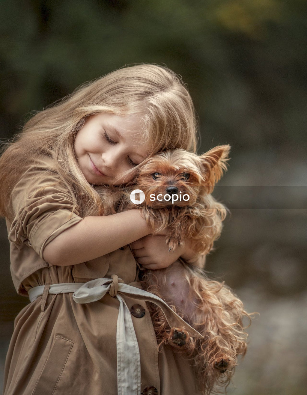 Girl in brown dress hugging brown long coated small dog
