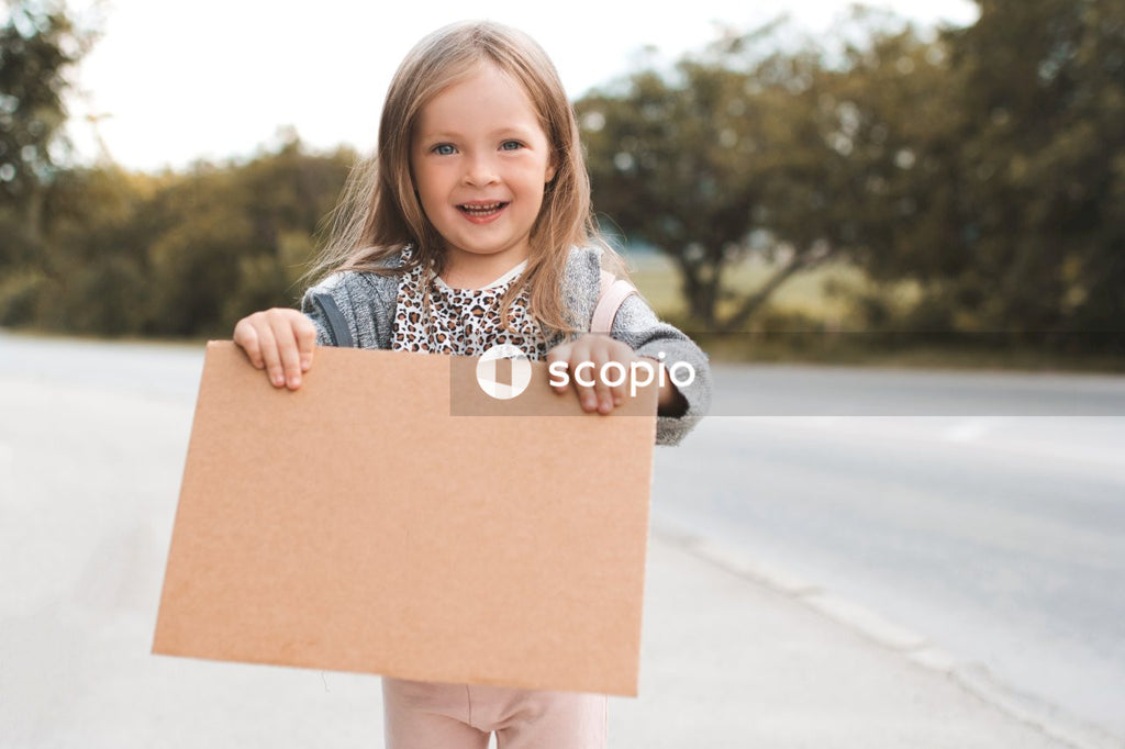 Girl in gray long sleeve shirt holding brown cardboard box