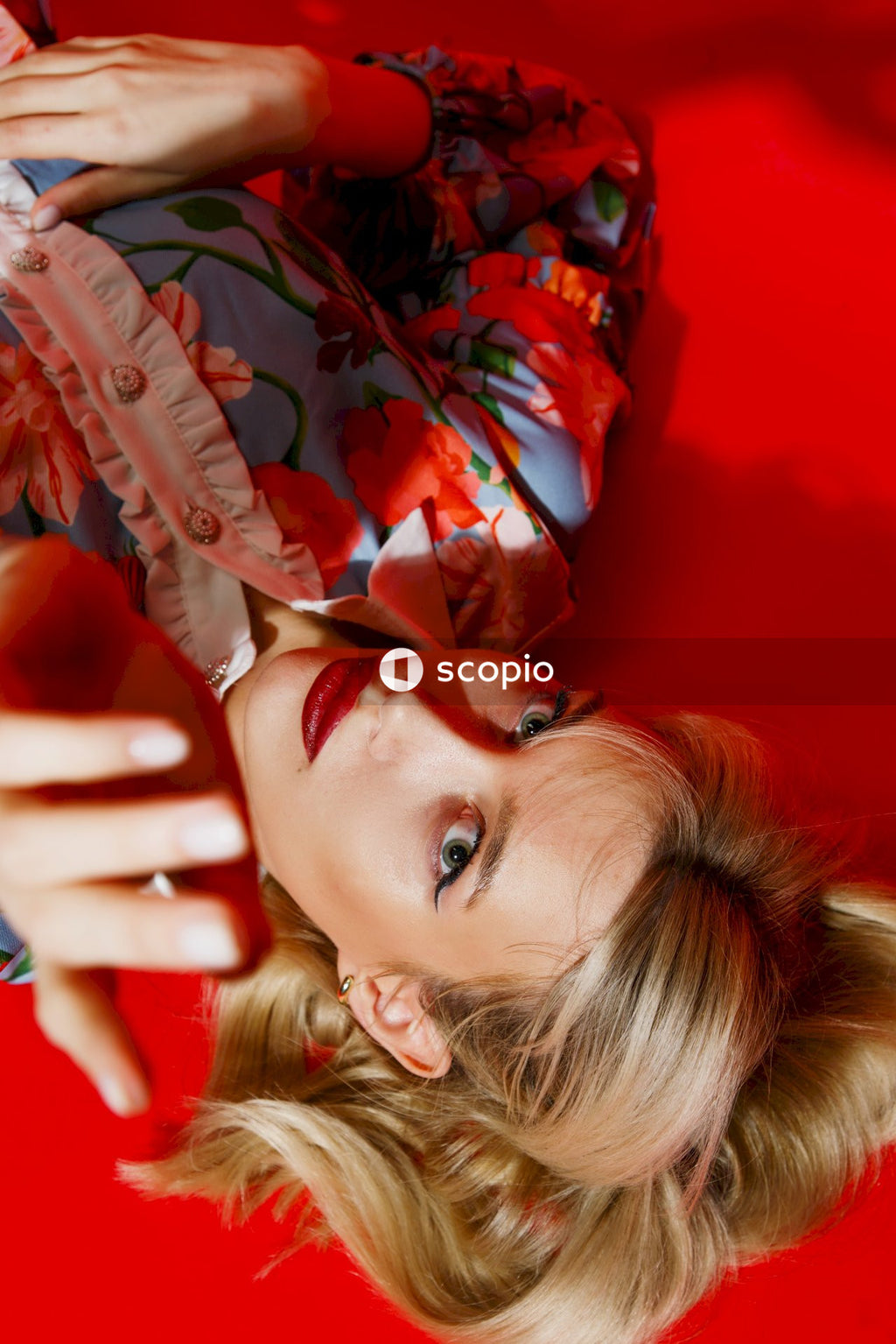 Girl in red and black floral dress lying on red textile