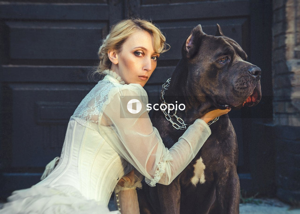 Girl in white dress hugging black and white short coated dog