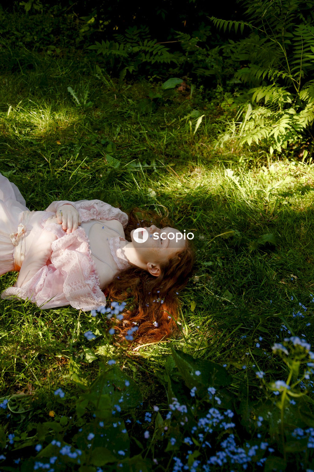 Girl in white dress lying on green grass