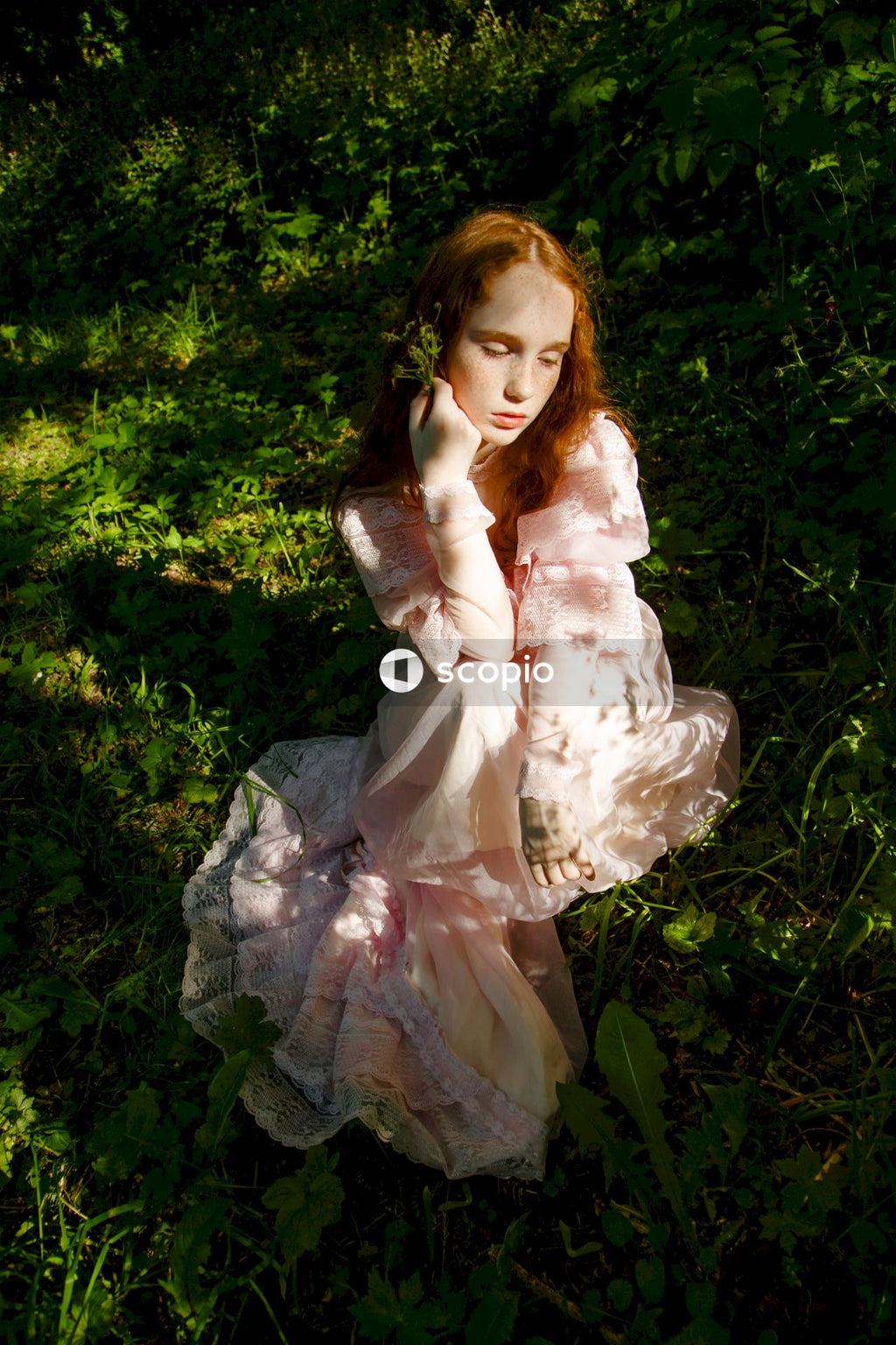 Girl in white dress sitting on green grass