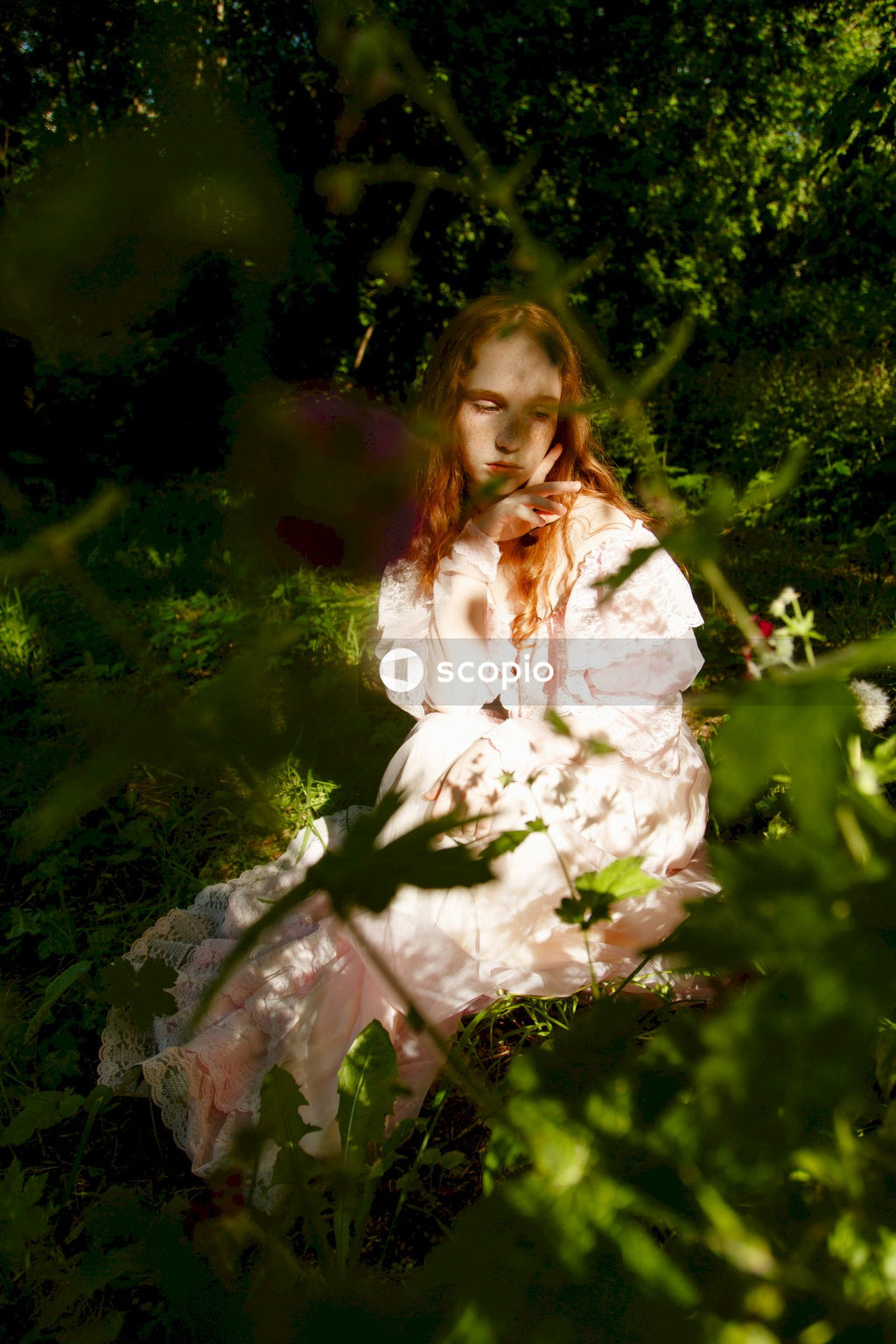 Girl in white dress sitting on green grass