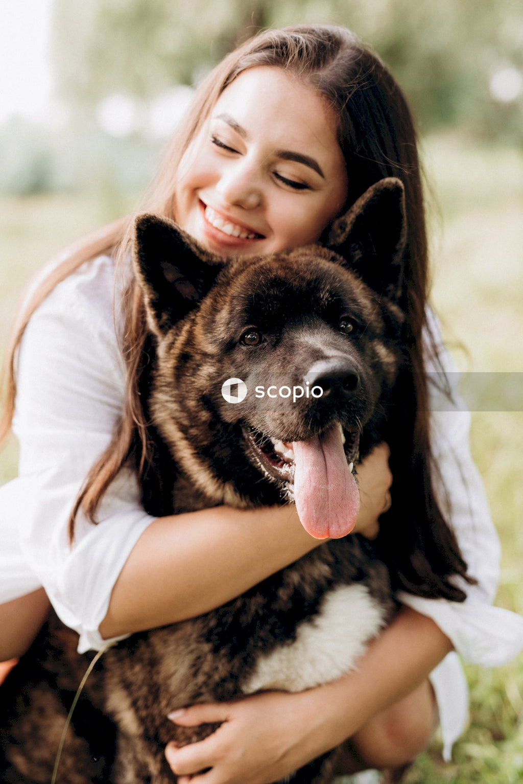 Girl in white shirt hugging black and brown short coated dog