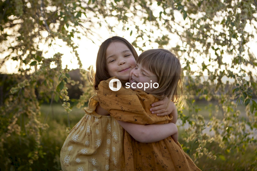 Girl in yellow dress hugging girl in brown dress