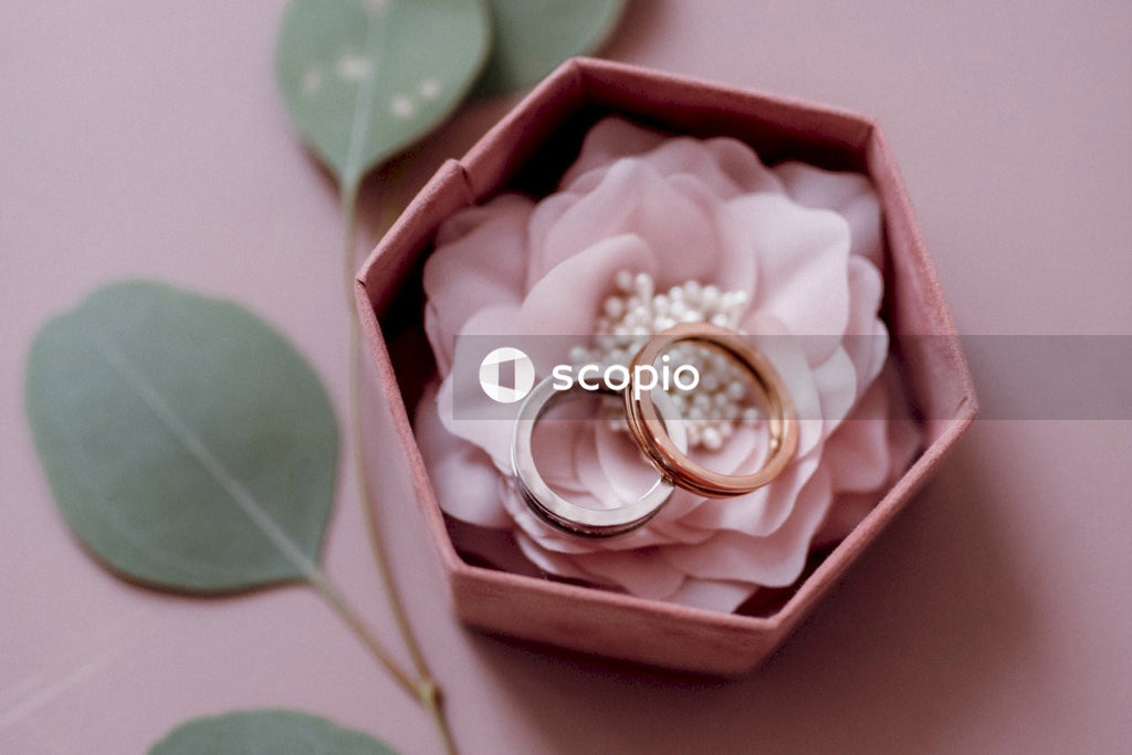 Gold and silver rings placed in box with pink background and decorated with Green Leaf and flower