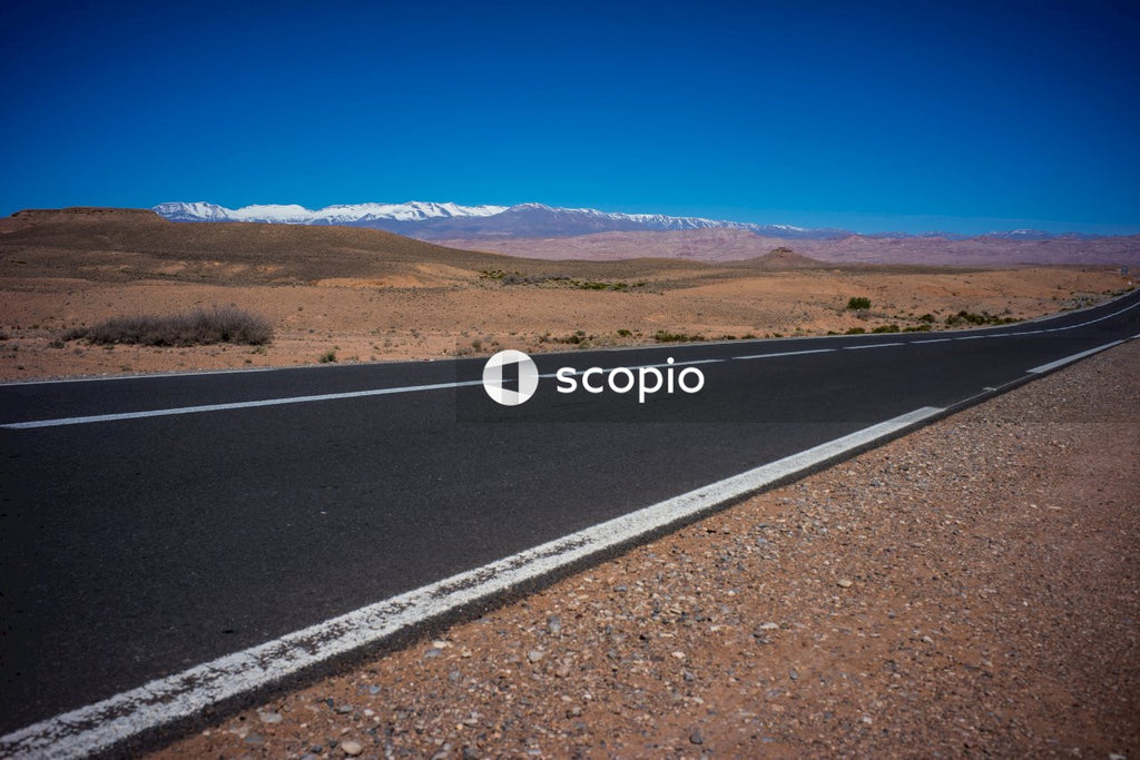 Gray asphalt road near brown field under blue sky