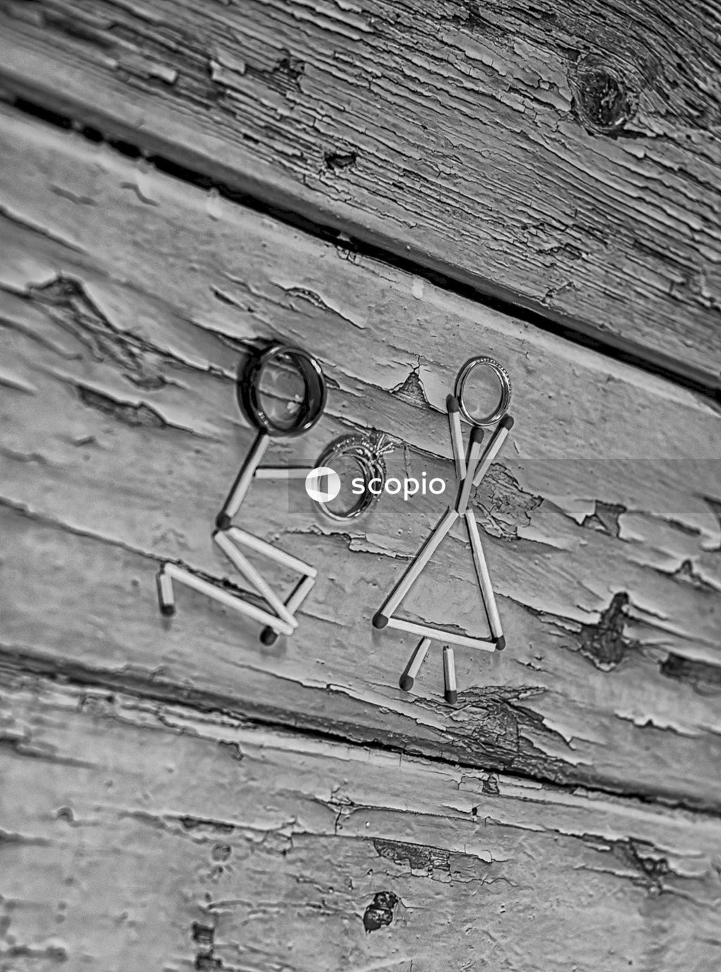 Grayscale photo of match sticks represent a man proposing to a woman with wedding ring