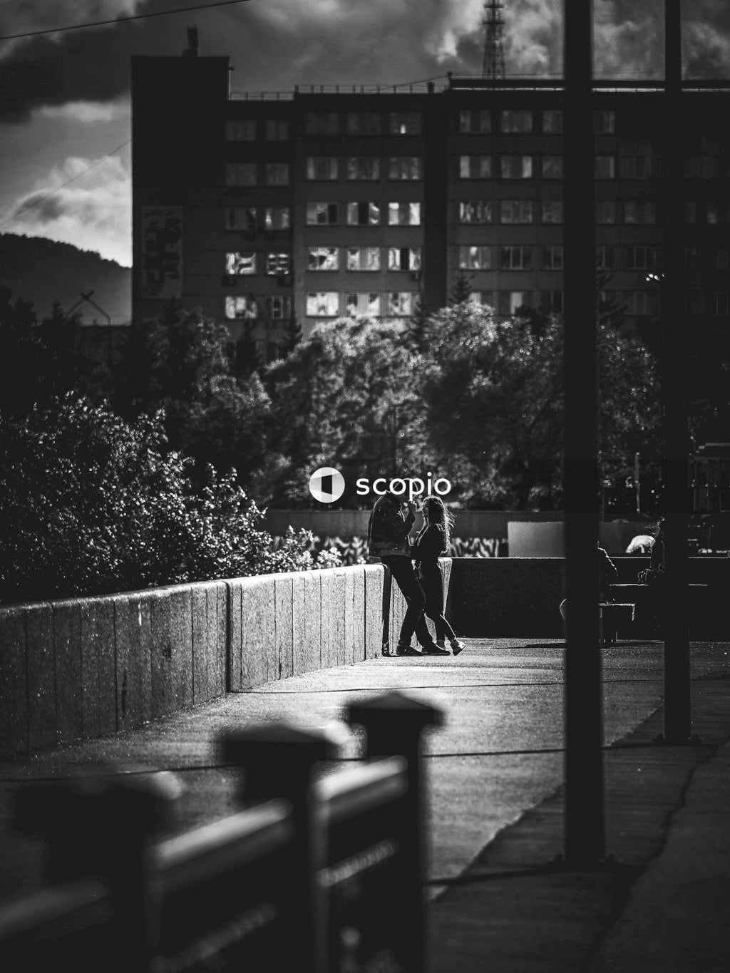 Grayscale image of man and woman having romantic moments outdoor near a building