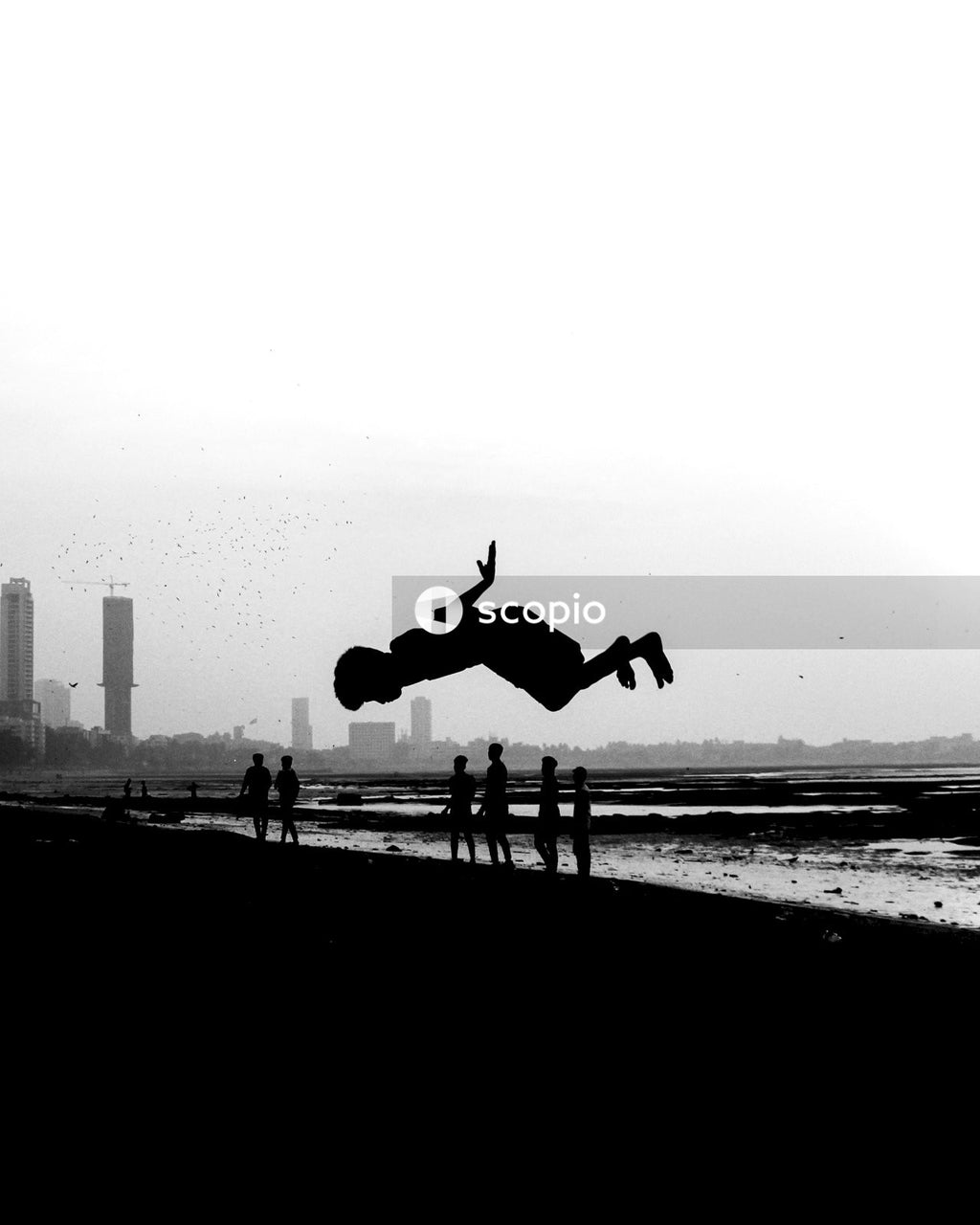 Grayscale photo of 1 person jumping on beach