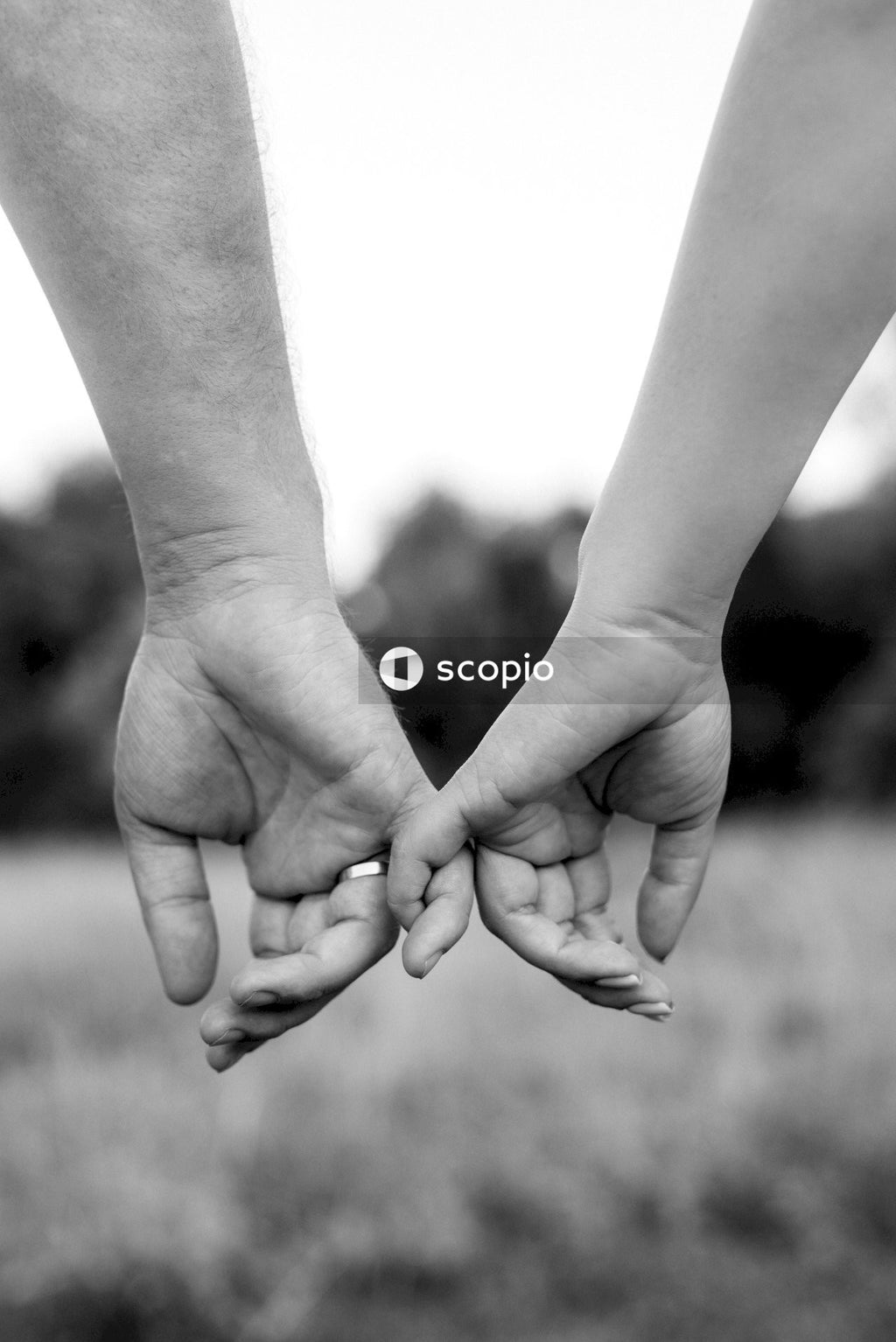 Grayscale photo of two people holding hands