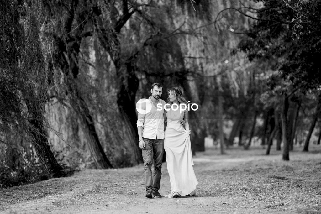 Grayscale photo of couple kissing near trees