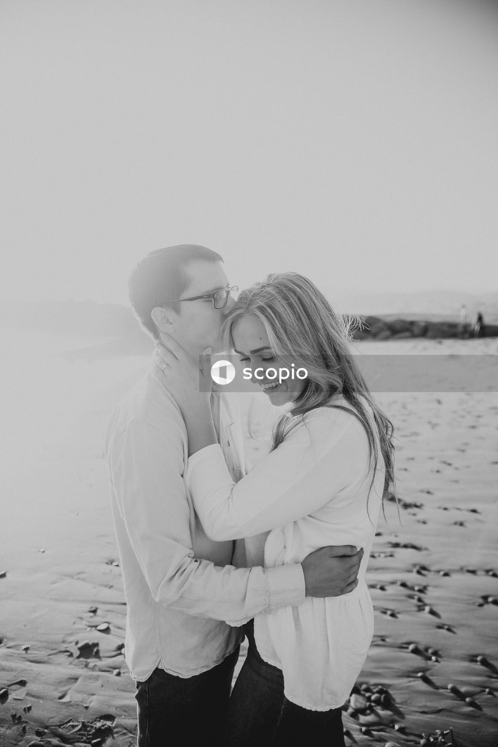 Grayscale photo of couple kissing on beach