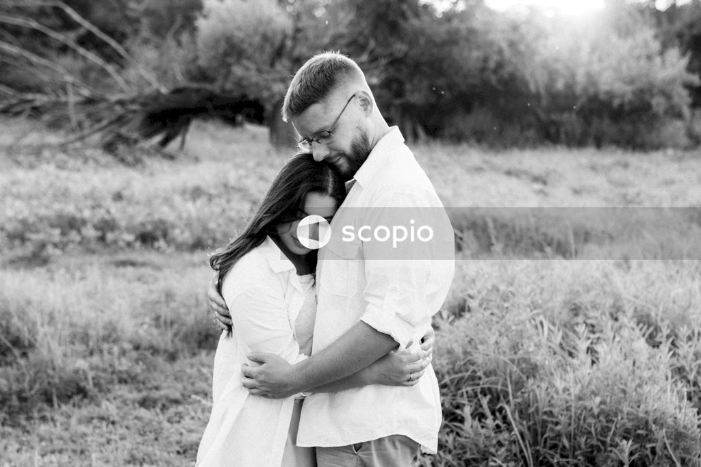 Grayscale photo of couple kissing on grass field