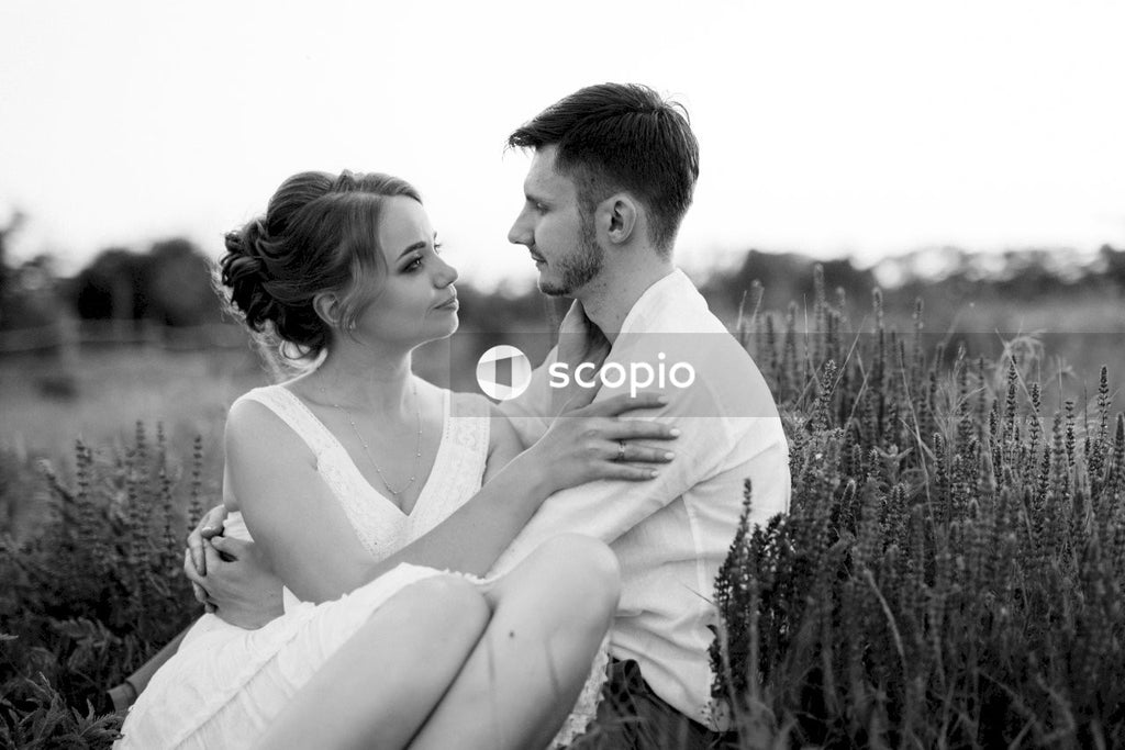 Grayscale photo of couple kissing on grass field