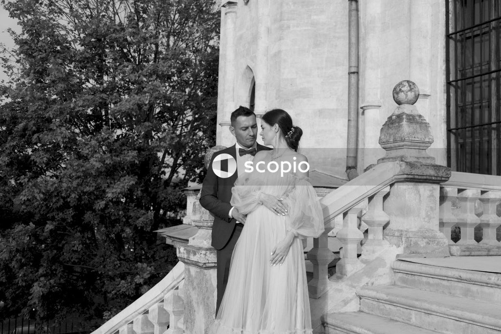 Grayscale photo of couple standing near concrete building