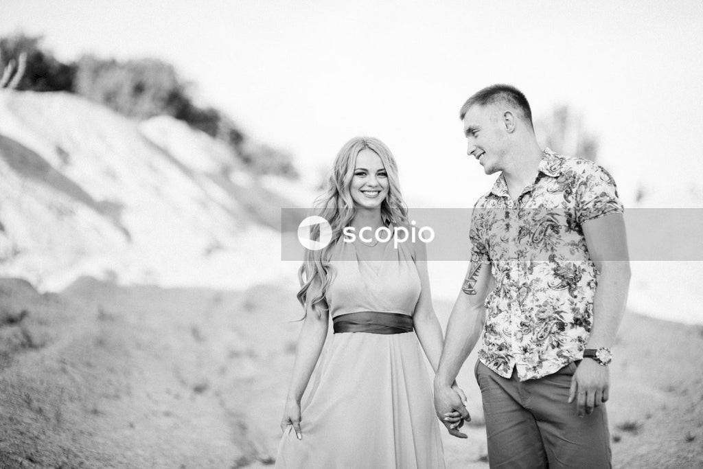 Grayscale photo of couple standing on sand